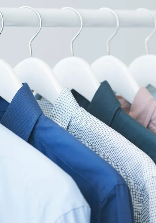 Freshly dry-cleaned blue dress shirts on wooden hangers